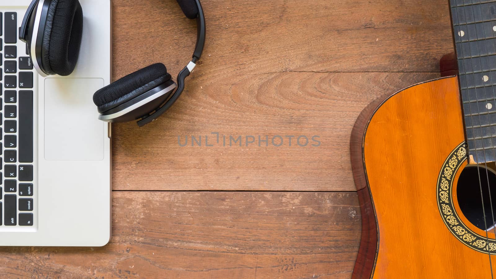 Top view workspace with laptop,headphone and acoustic guitar on wooden table background .Free space for your text. by ronnarong