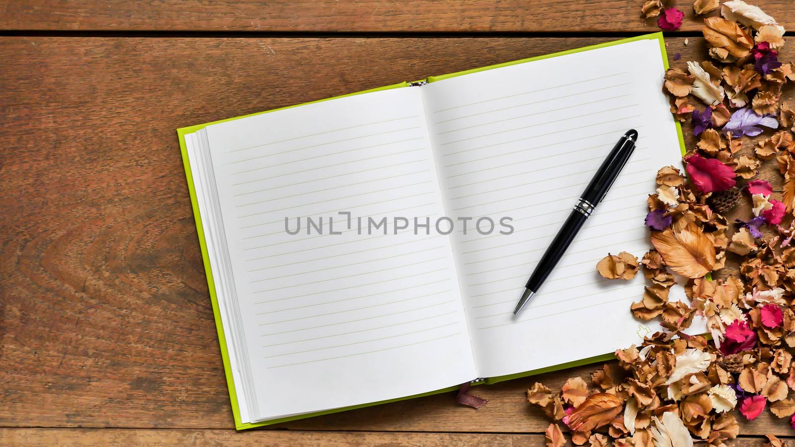 Top view workspace with blank notebook,pen and dried flowers on wooden table background.