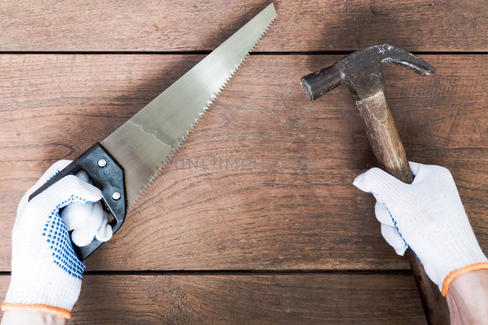 Hands holding hammer  and saw on wooden table background.