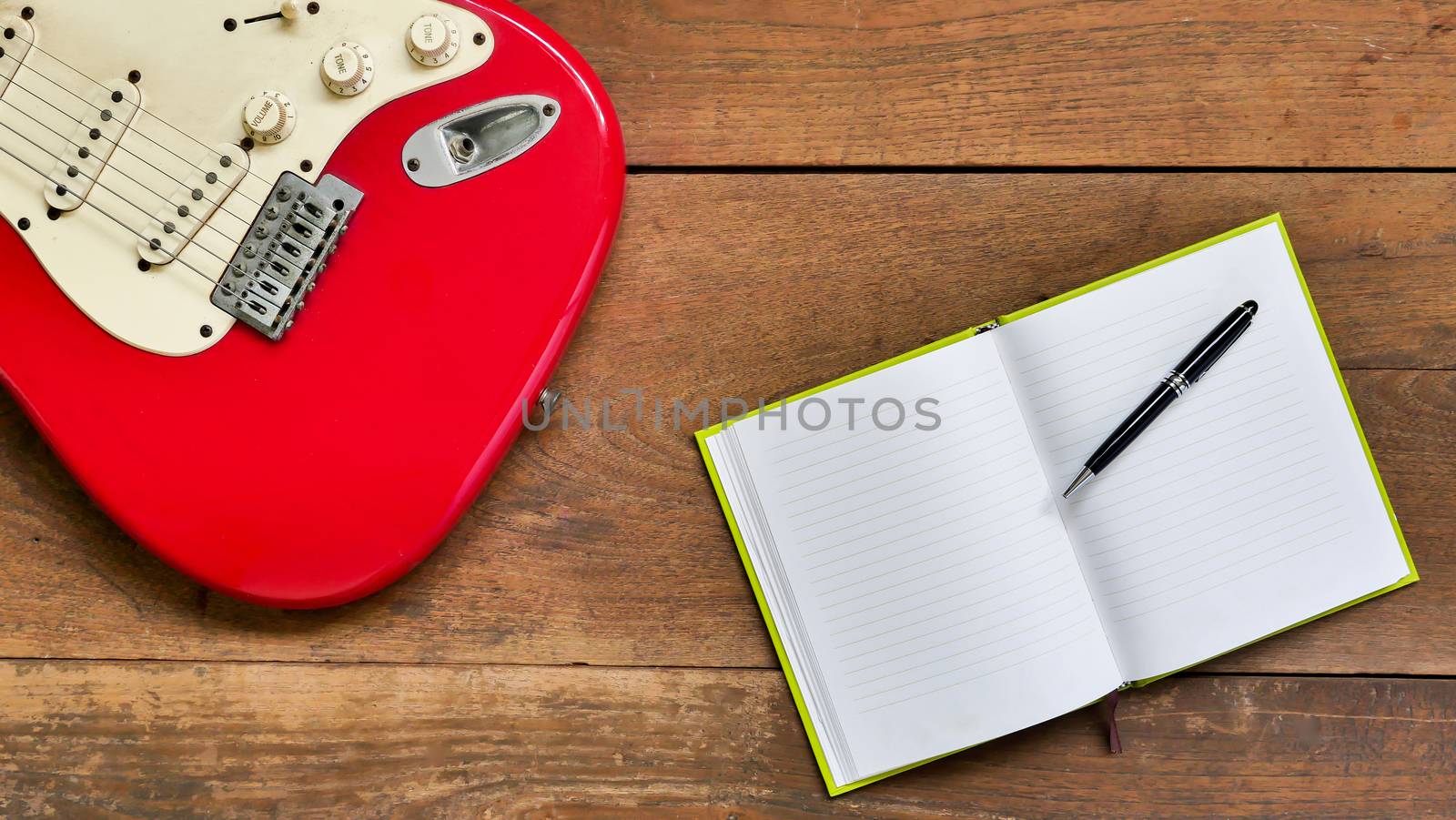 Top view workspace with blank notebook,pen and Electric guitar on wooden table background . by ronnarong