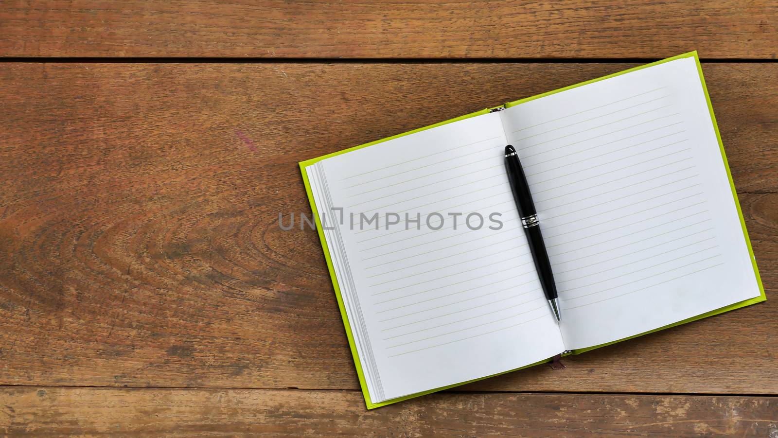 Top view workspace with blank notebook and pen on wooden table background .