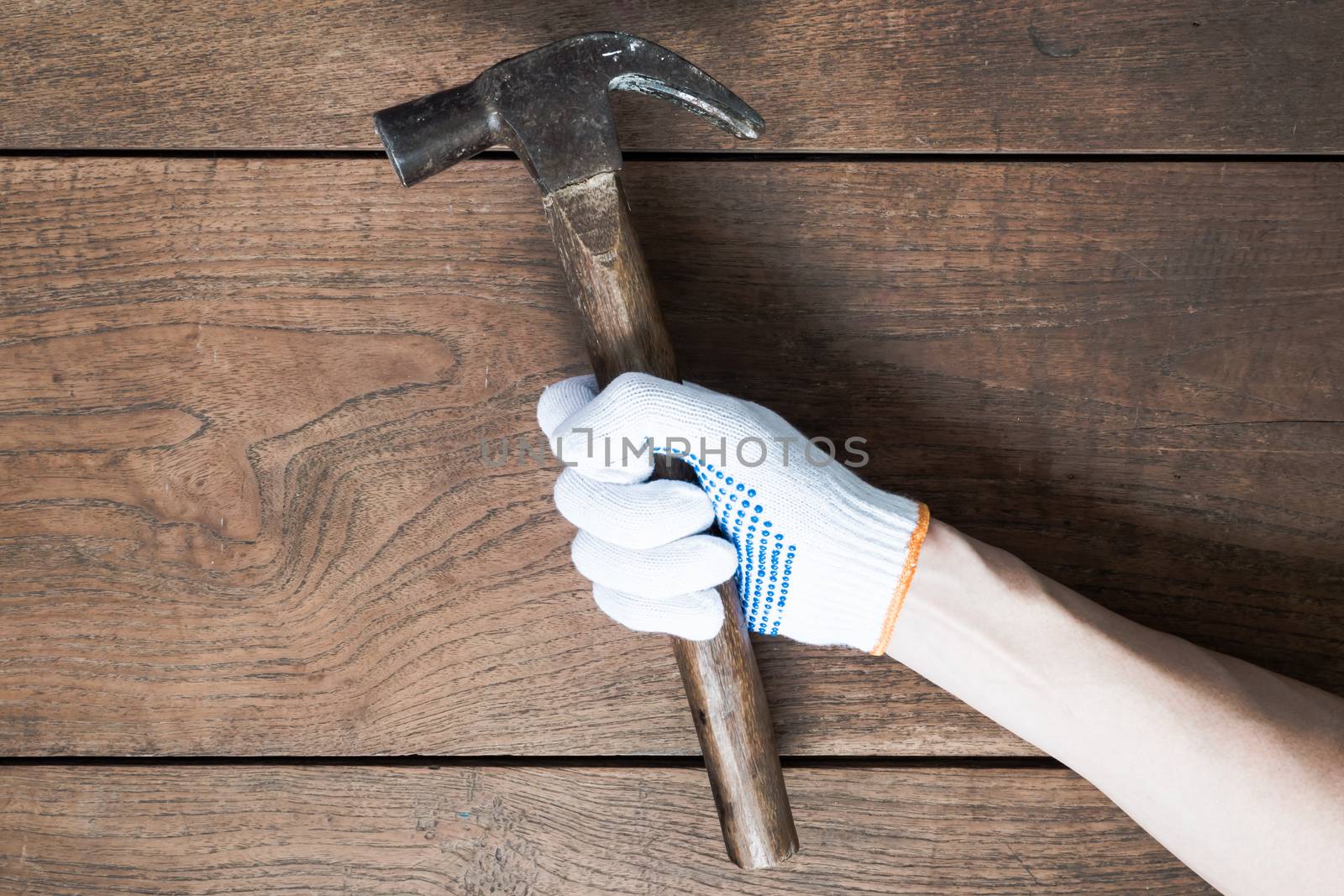 Hand holding hammer on wooden table background.