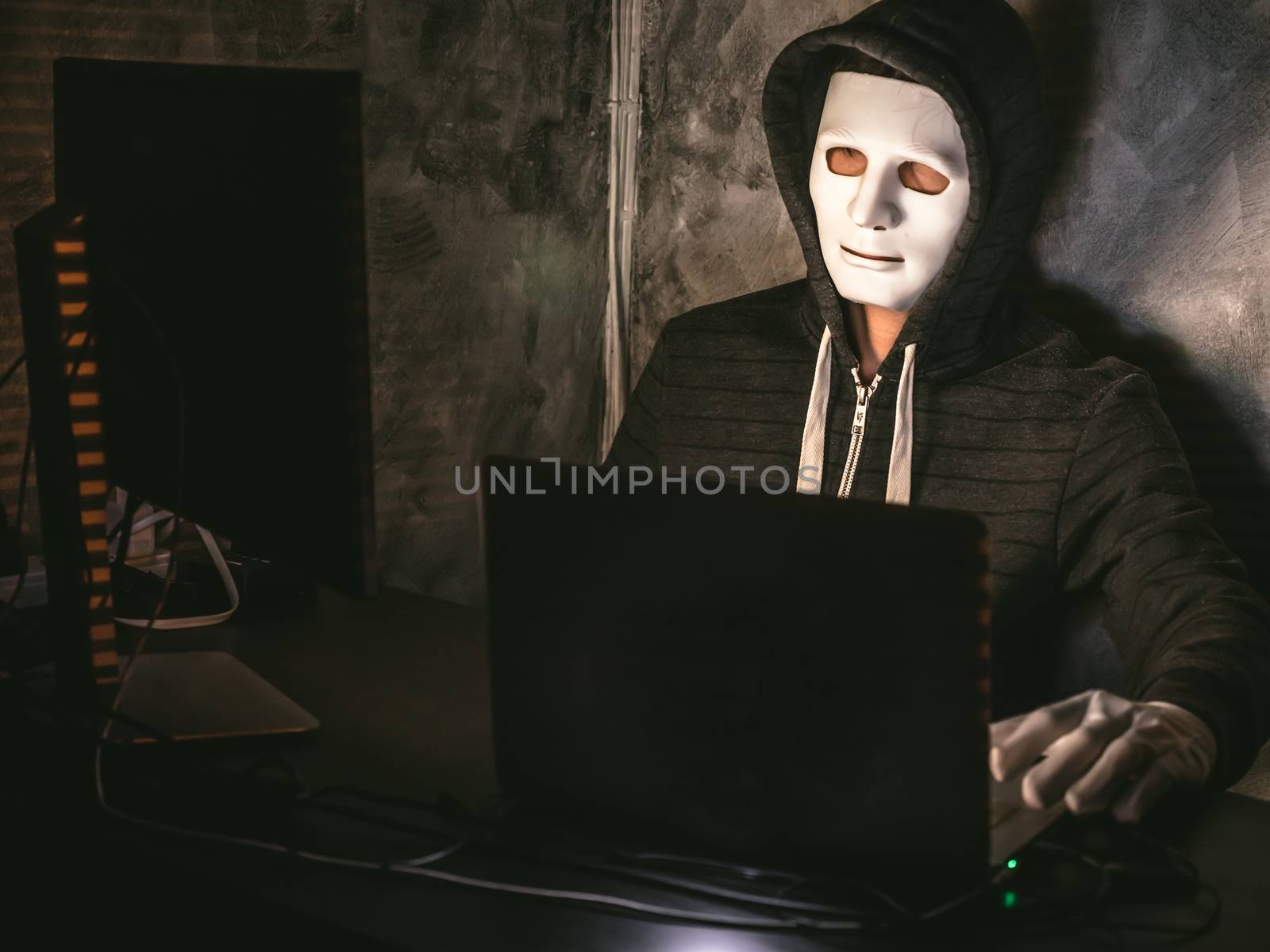 Computer hacker - Man in hoodie shirt with mask stealing data from laptop by ronnarong