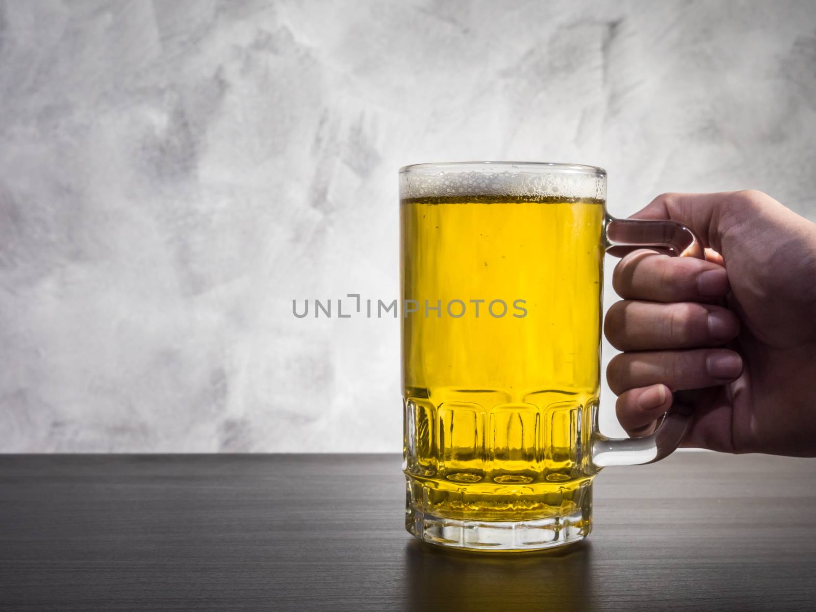 Hand Holding Glass of beer on a grunge background.