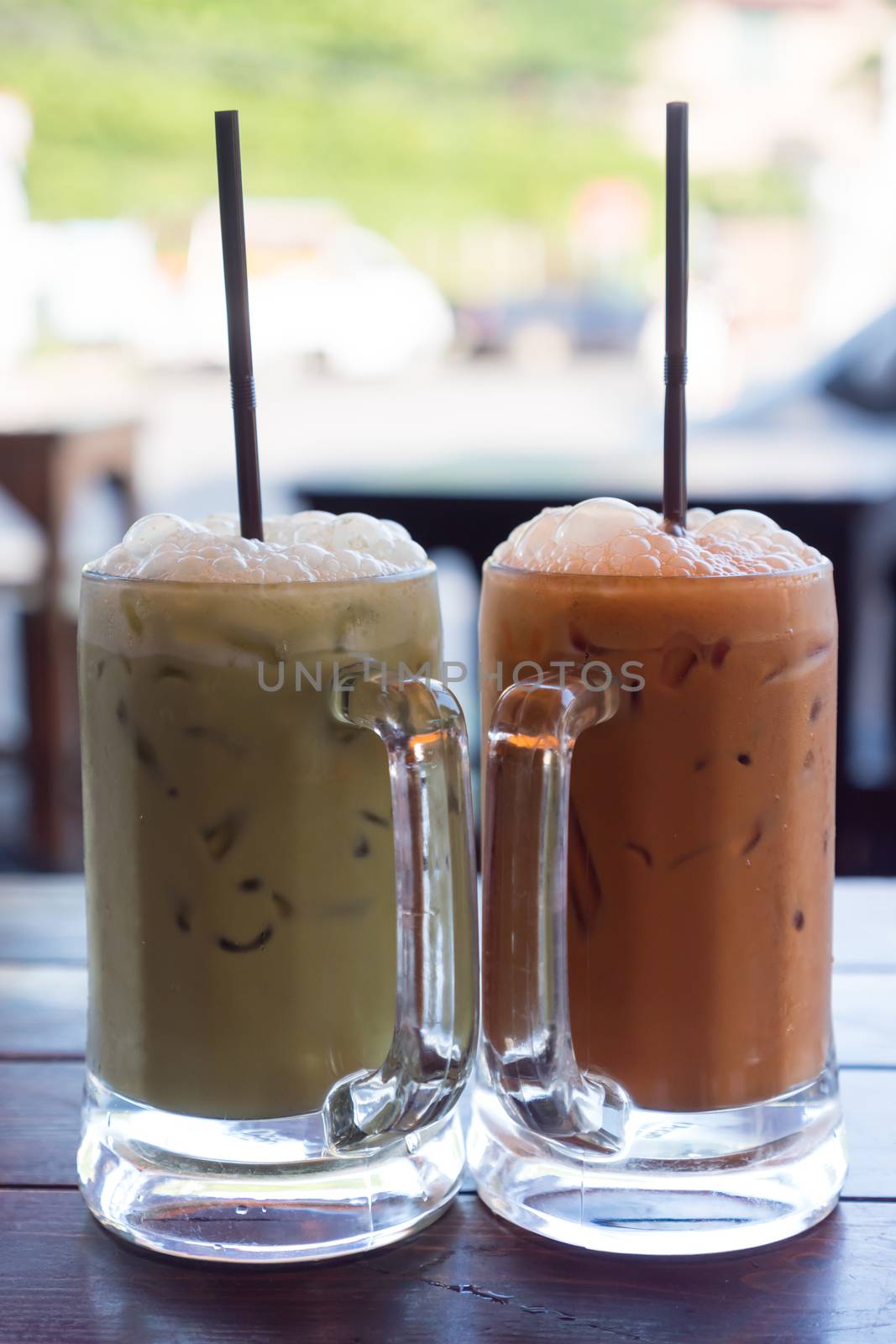 Milk green tea and milk thai tea in glass mugs on wood table. by ronnarong