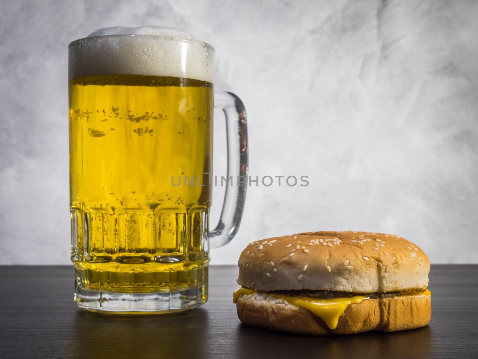 Hamburger with Glass of beer on the table over a grunge background.