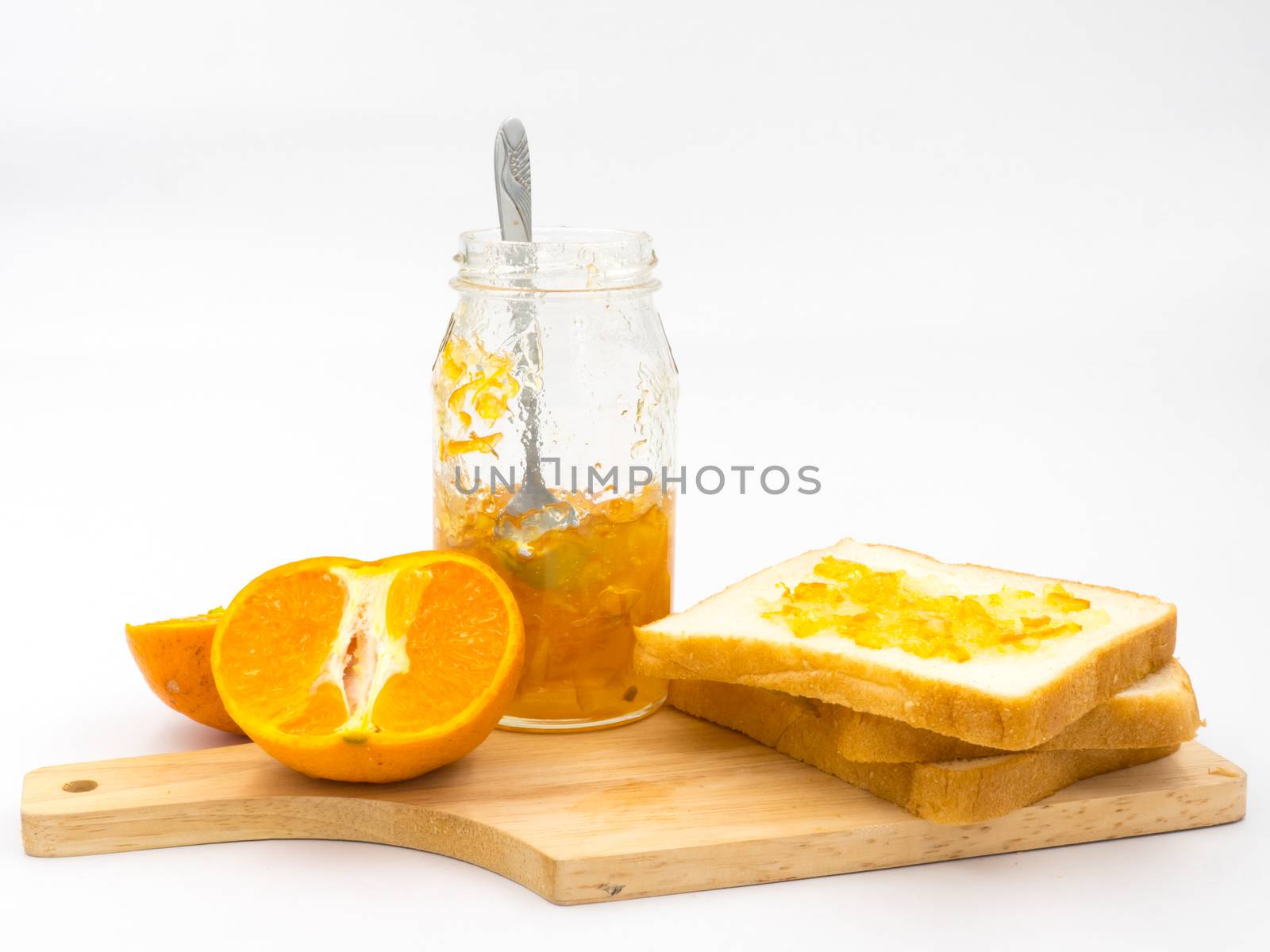 Fresh orange with orange jam in glass jar and  bread on wooden tray over white background.