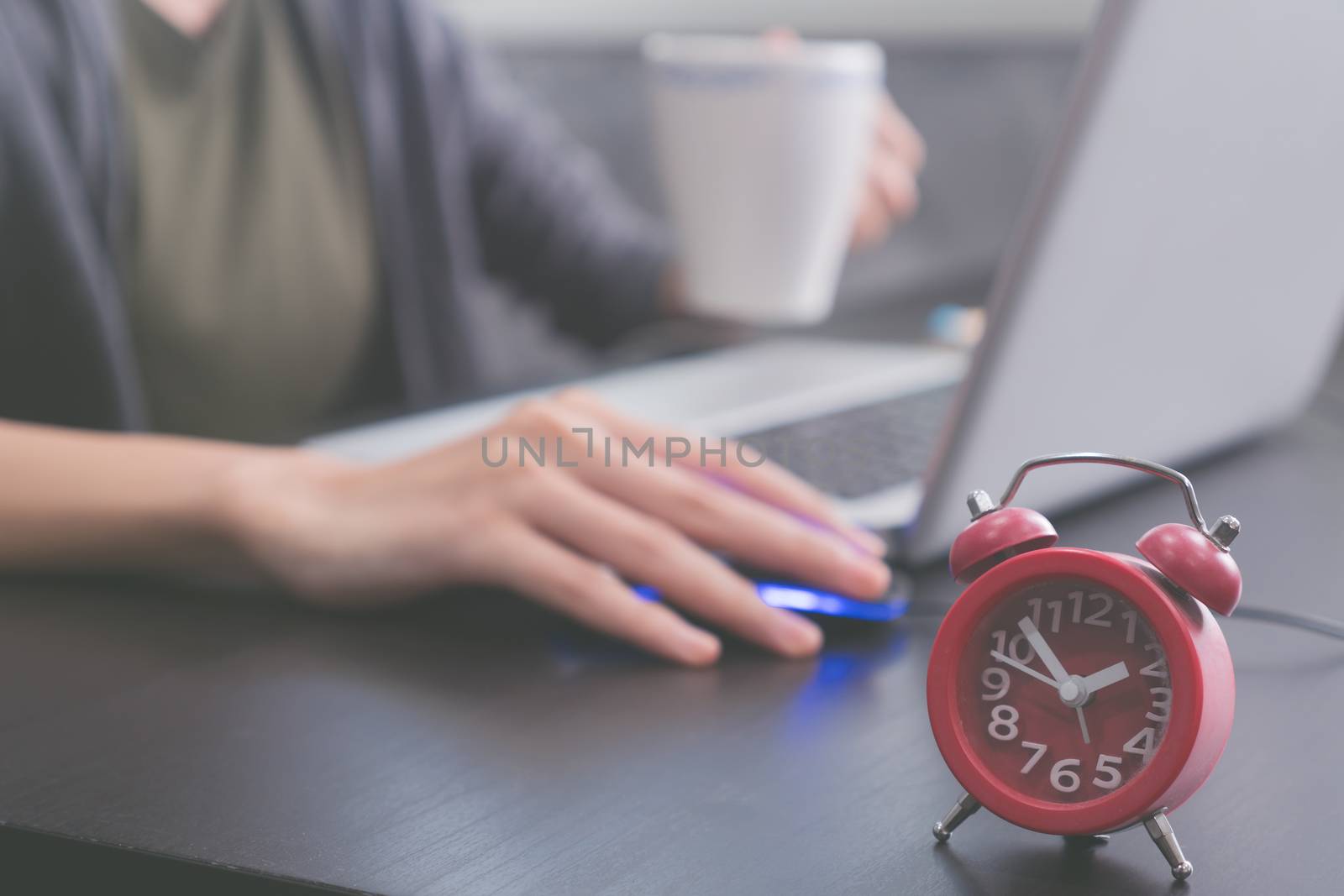 Close up of red clock on the desk, Afternoon time, Casual young woman using a laptop