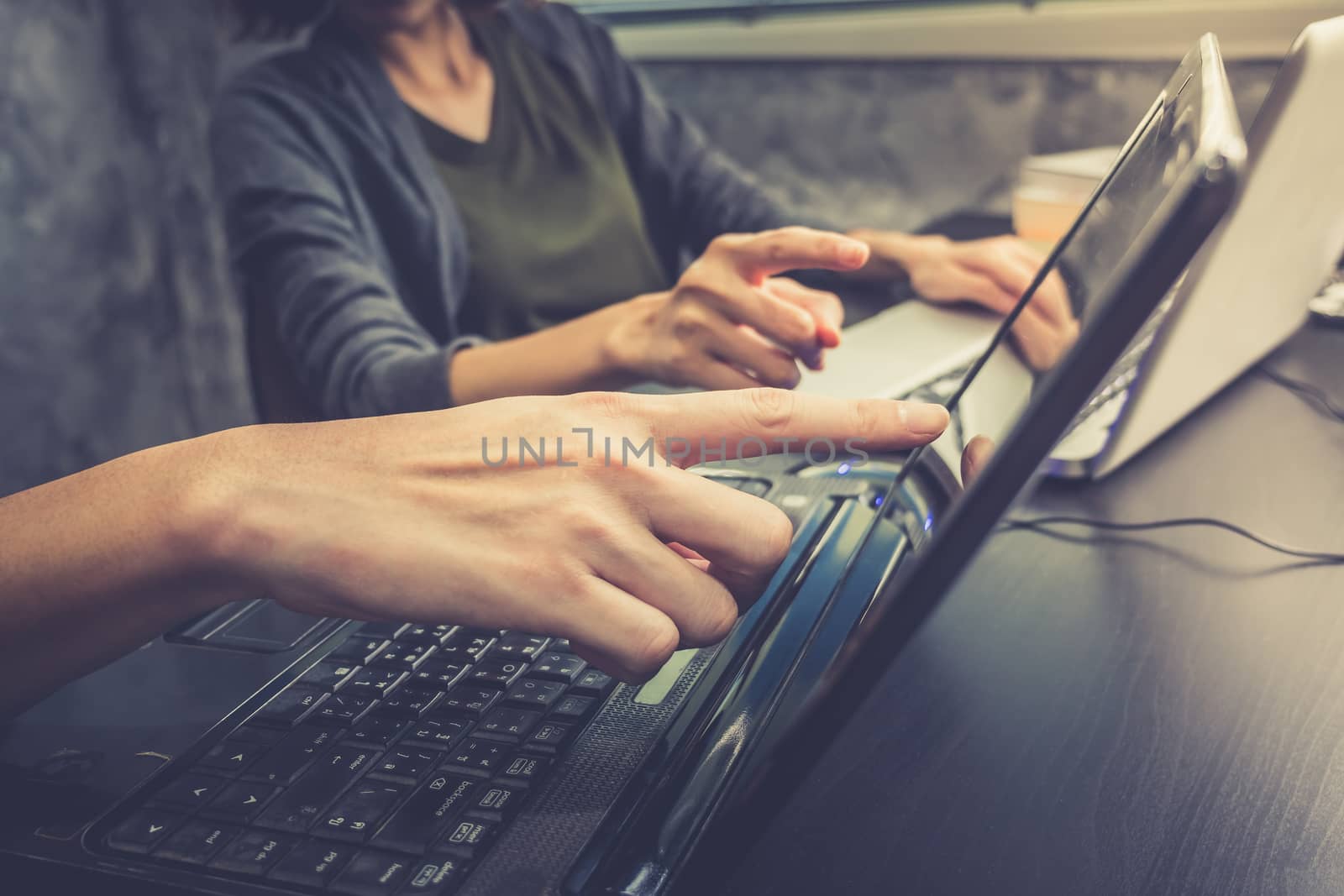 Business partners working together on the same desk, they are using a laptop, Vintage tone