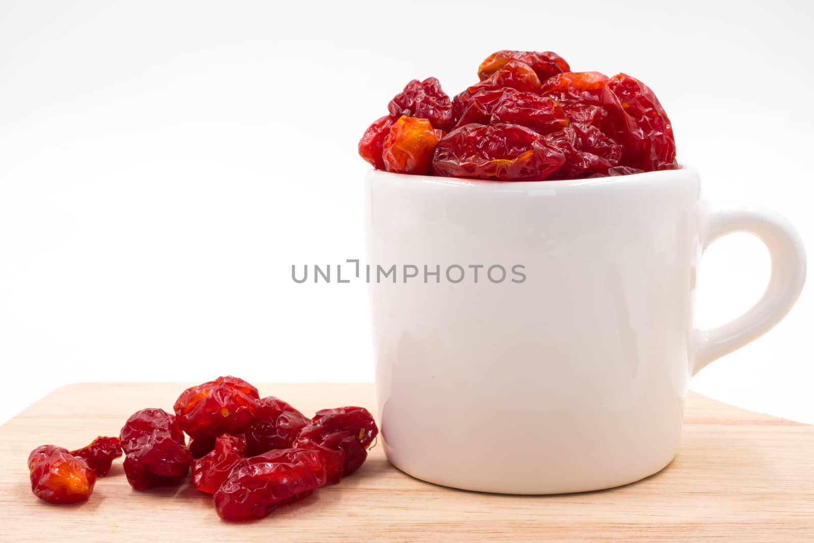 Dried Tomatoes in cup  on wooden tray.