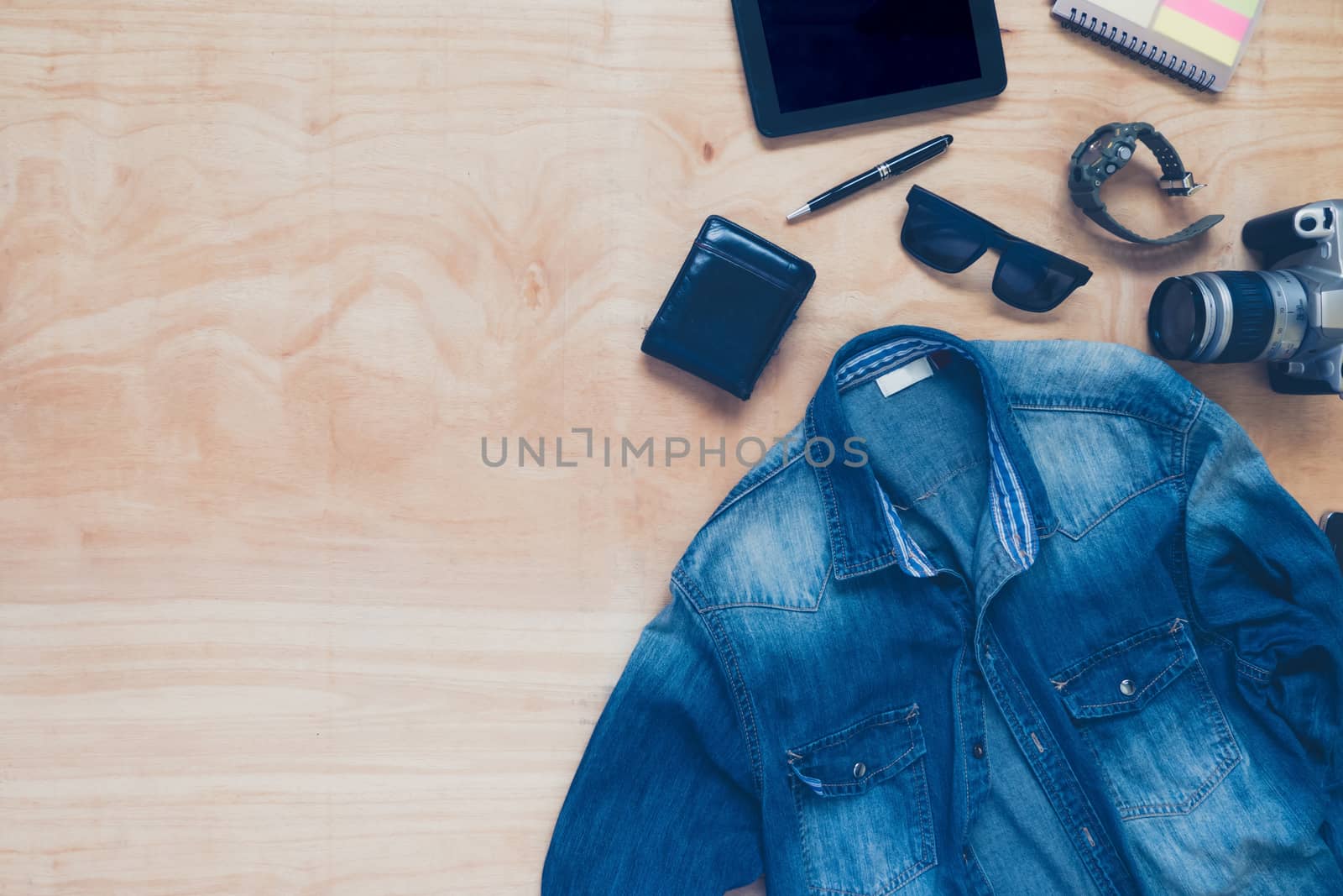 Top view of clothing and diverse personal accessory on the wooden table background.