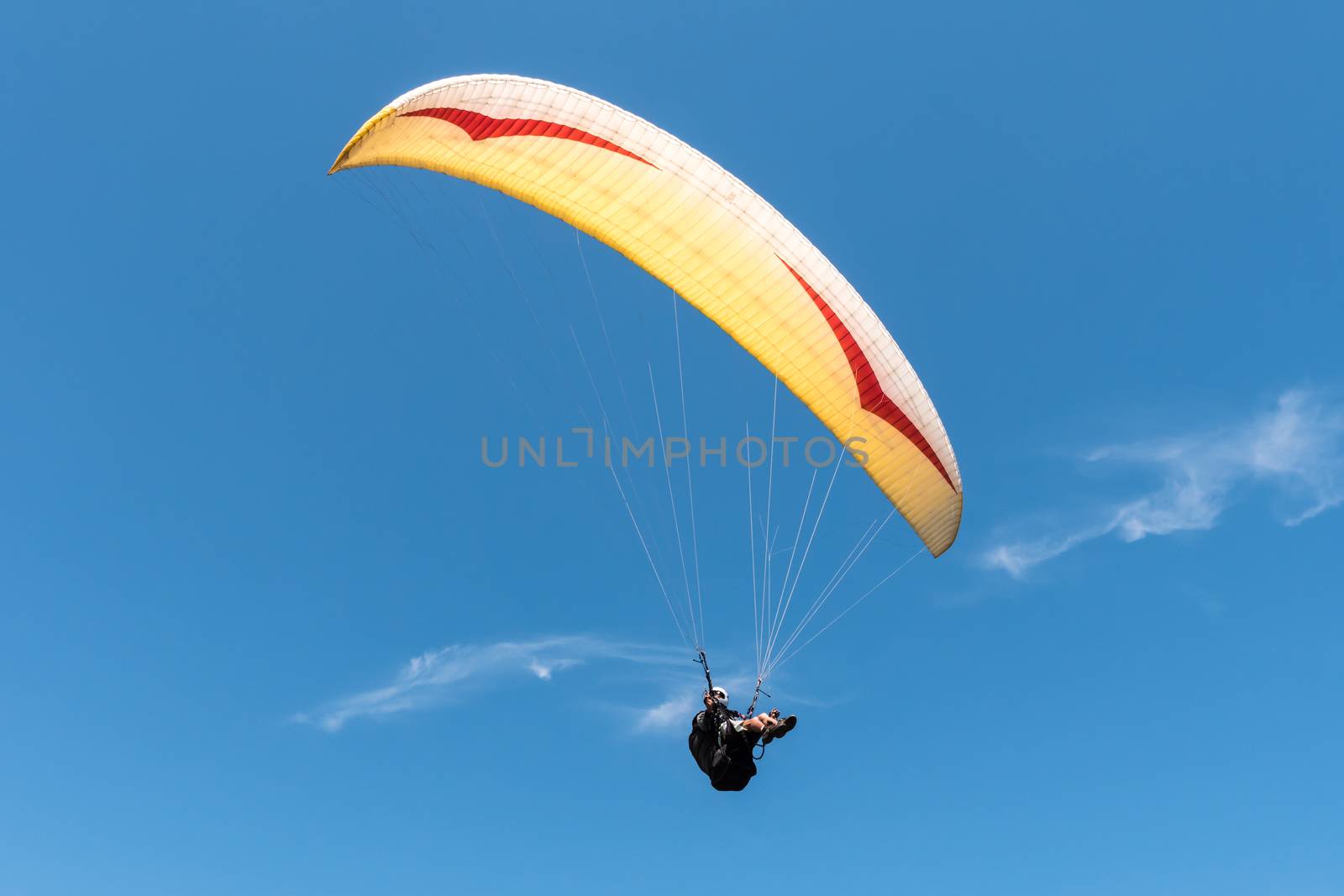 Paraglider flying in blue sky.