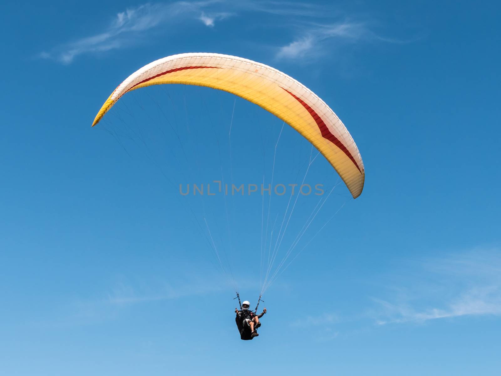 Paraglider flying in blue sky.