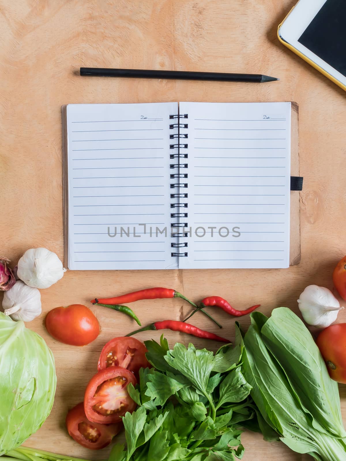 Top view of Fresh vegetables with blank notebook on wooden table background.