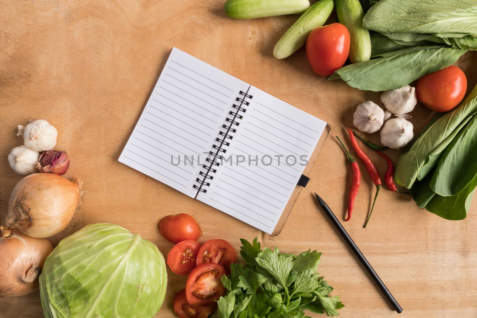 Top view of Fresh vegetables with blank notebook on wooden table background.