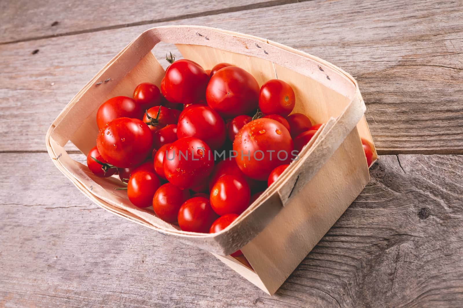 ripe tomatoes in a small wooden crate in studio