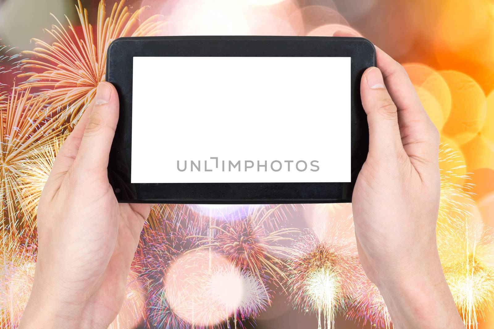 Male hand holding a tablet touch computer gadget with touch blank screen on firework and bokeh lights background.