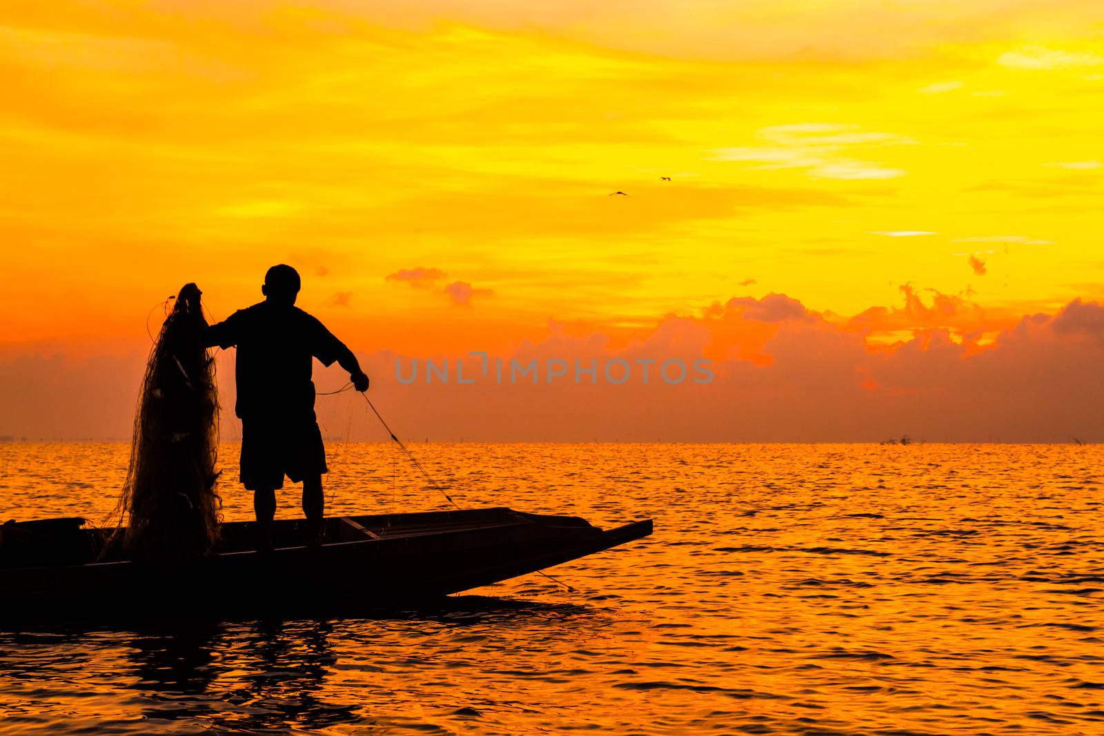 Silhouette of Fishermen fishing in the lake at the sunrise time.