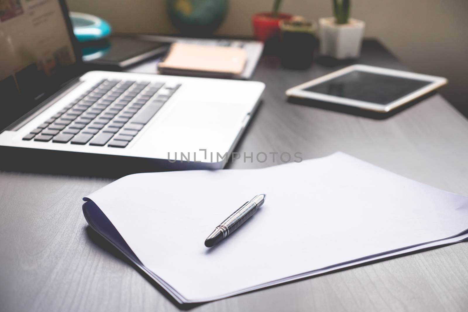 Blank Papers with pen,tablet and laptop on   the desk.