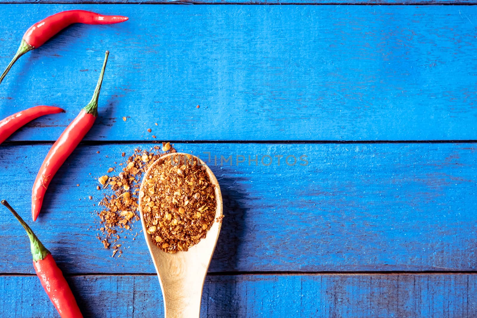 Top view of Red hot chilli peppers with cayenne on blue wooden table background, Free space for text