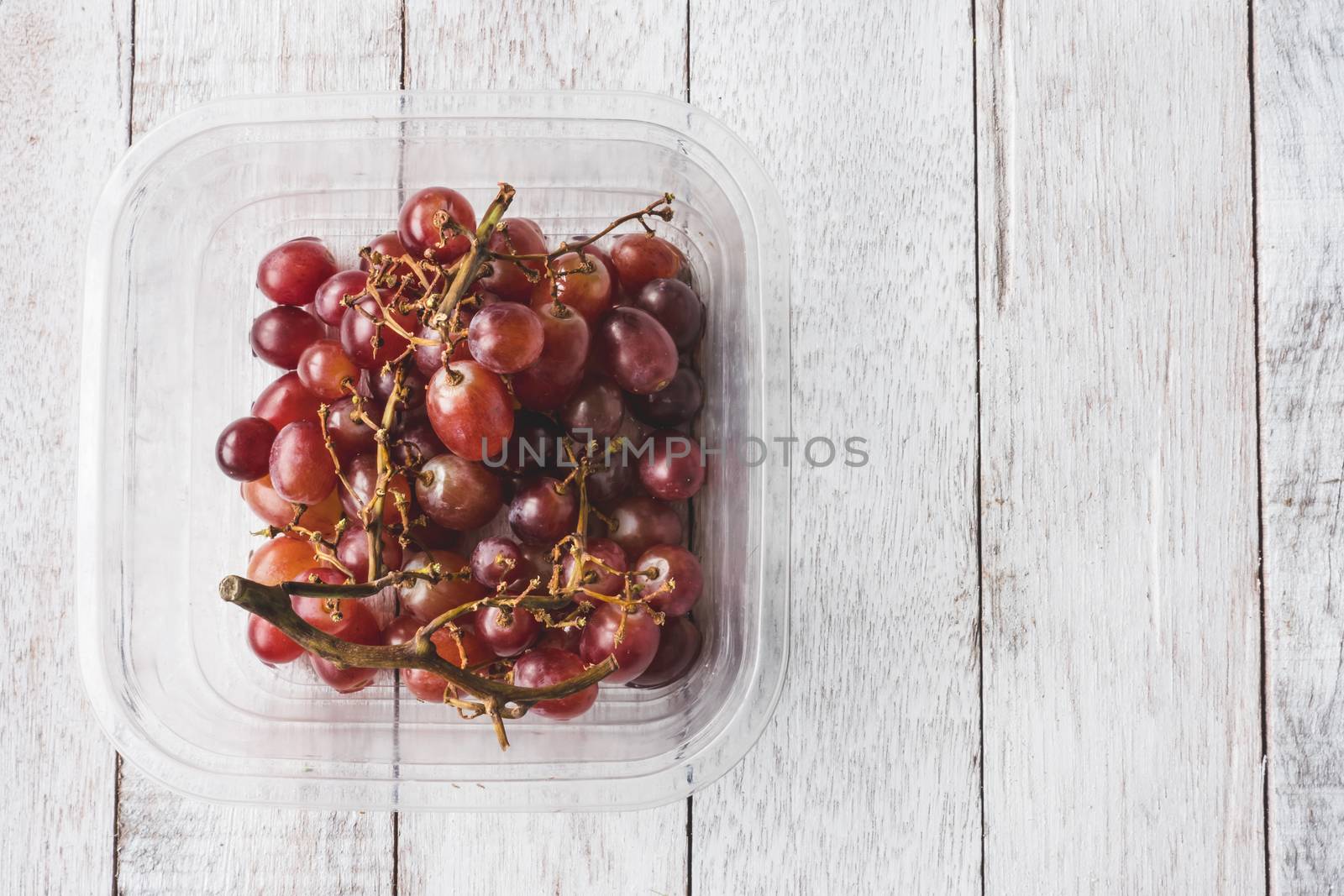 Top view of Red grapes on white wooden table background.