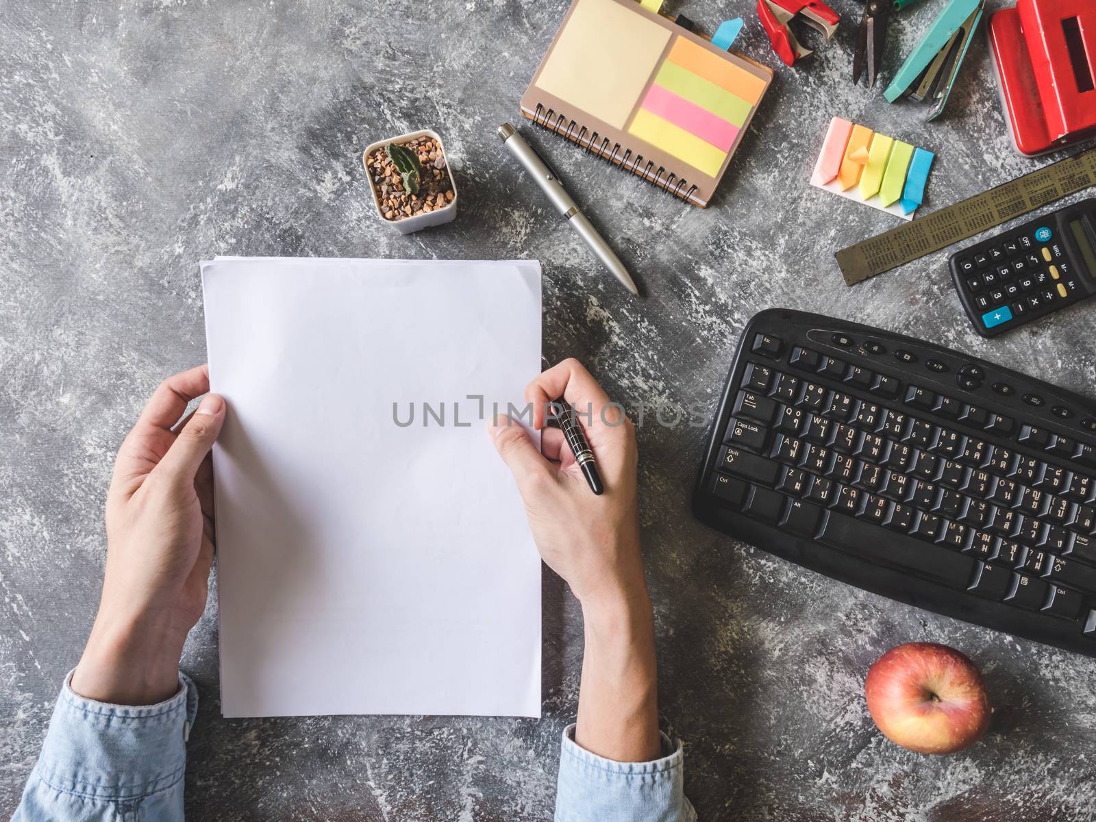 Top view of Male hands holding paper sheet with Office supplies on Grunge gray background