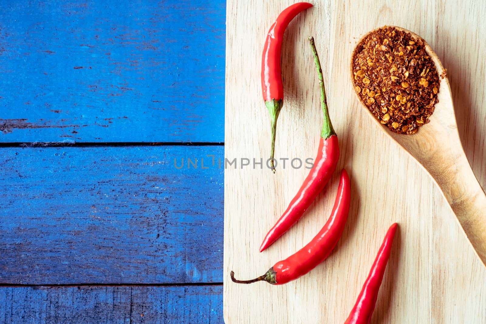 Top view of Red hot chilli peppers with cayenne on blue wooden table background, Free space for text