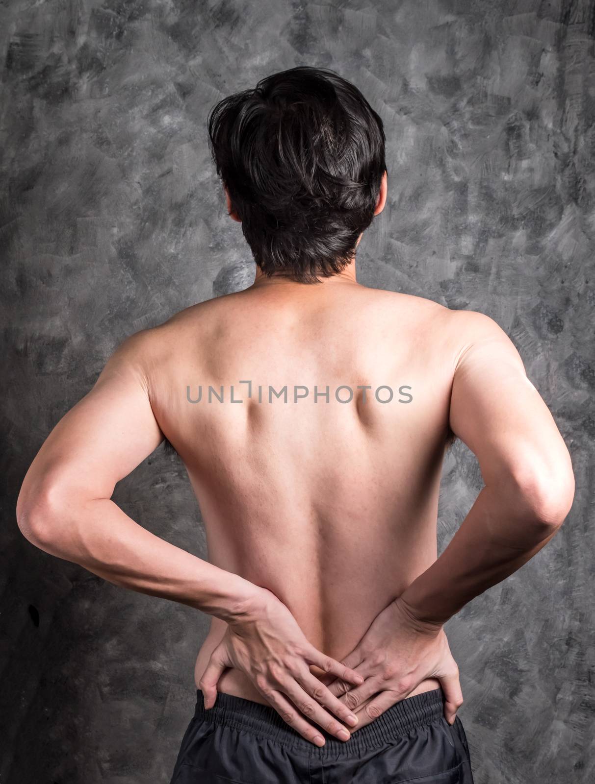a man with back pain on grey background