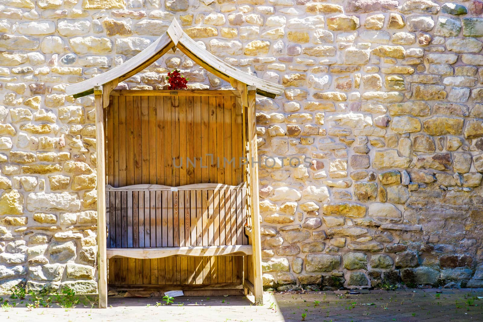 Wooden arbour in car park against a wall by paddythegolfer