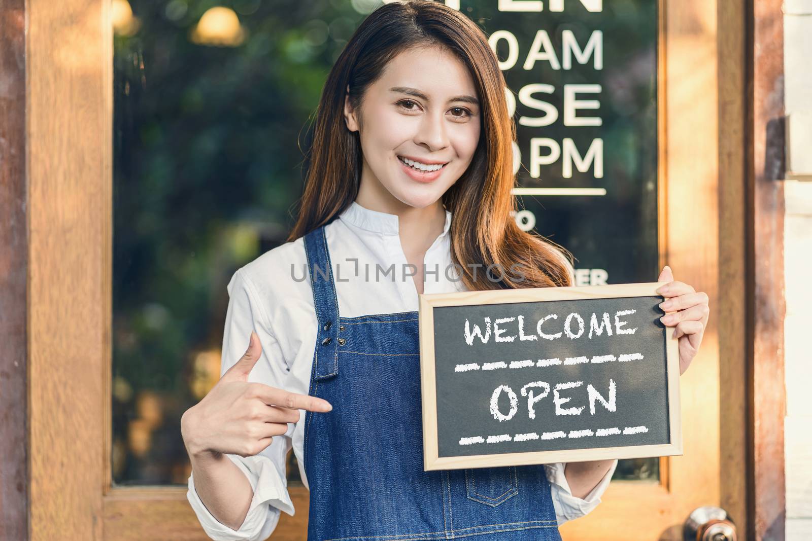 Asian Small business owner hands holding and showing the chalkboard with Welcome Open sign in front of coffee shop, startup with cafe store, installing open and close label concept
