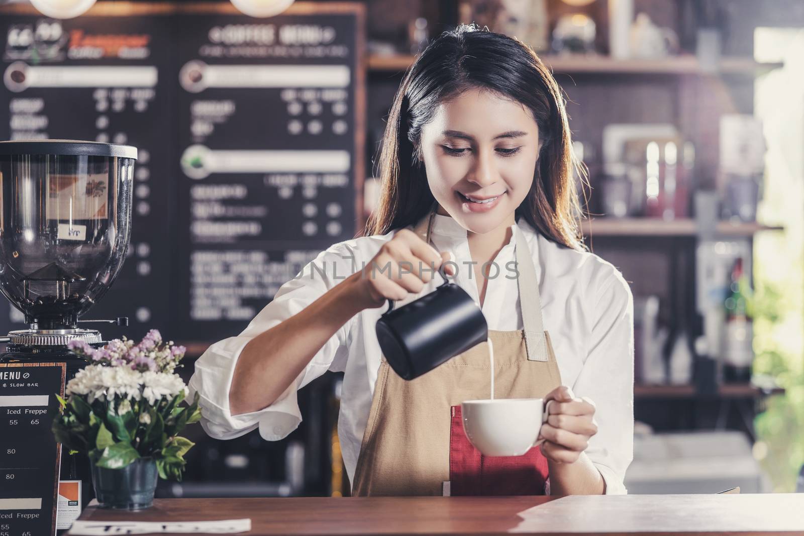 Asian Barista preparing cup of coffee, espresso with latte or cappuccino for customer order in coffee shop,bartender pouring milk,Small business owner and startup in coffee shop and restaurant concept