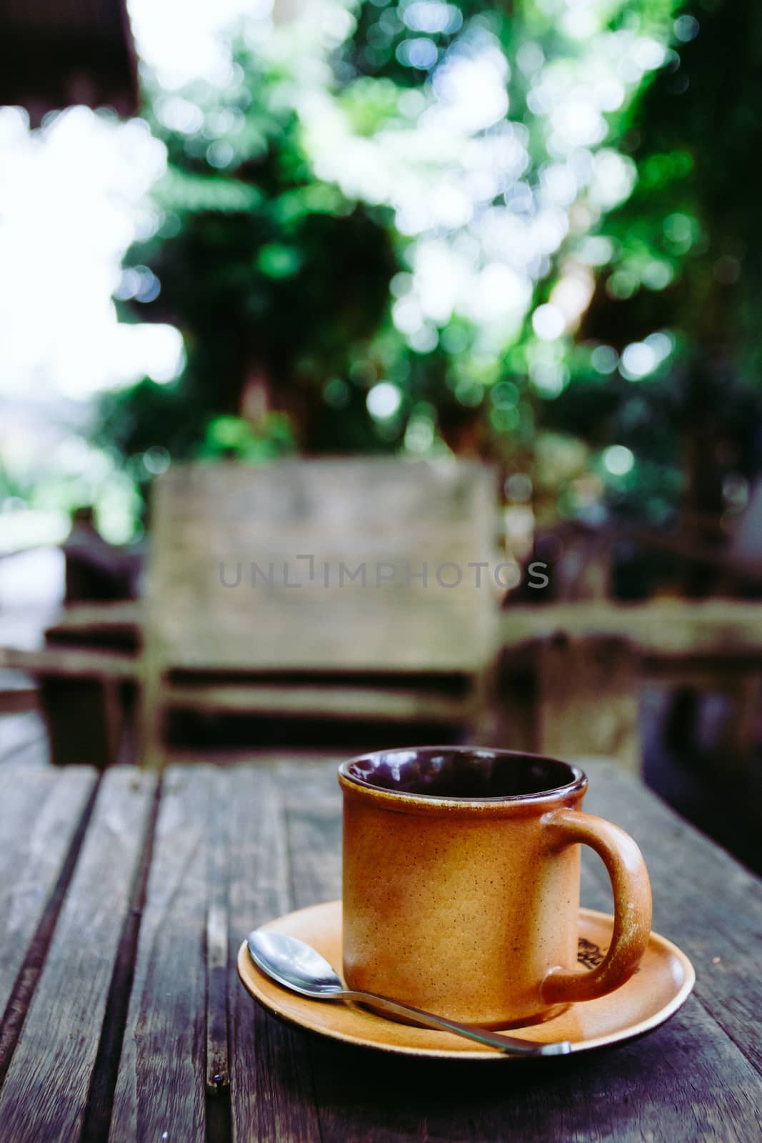 Cup of coffee on the wooden table in cafe. Films grain filter. by ronnarong