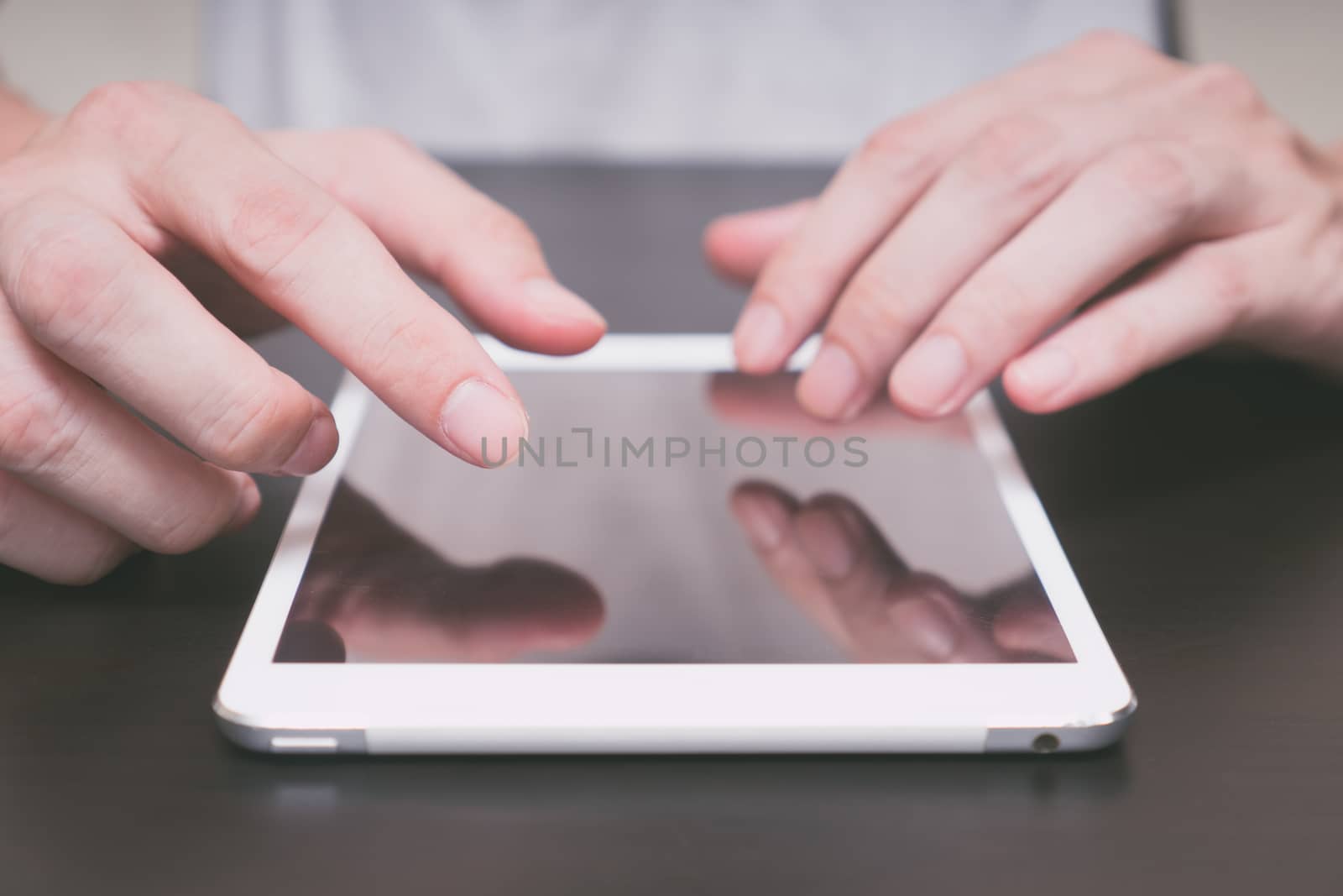 Close up of Male hands using tablet on the table.