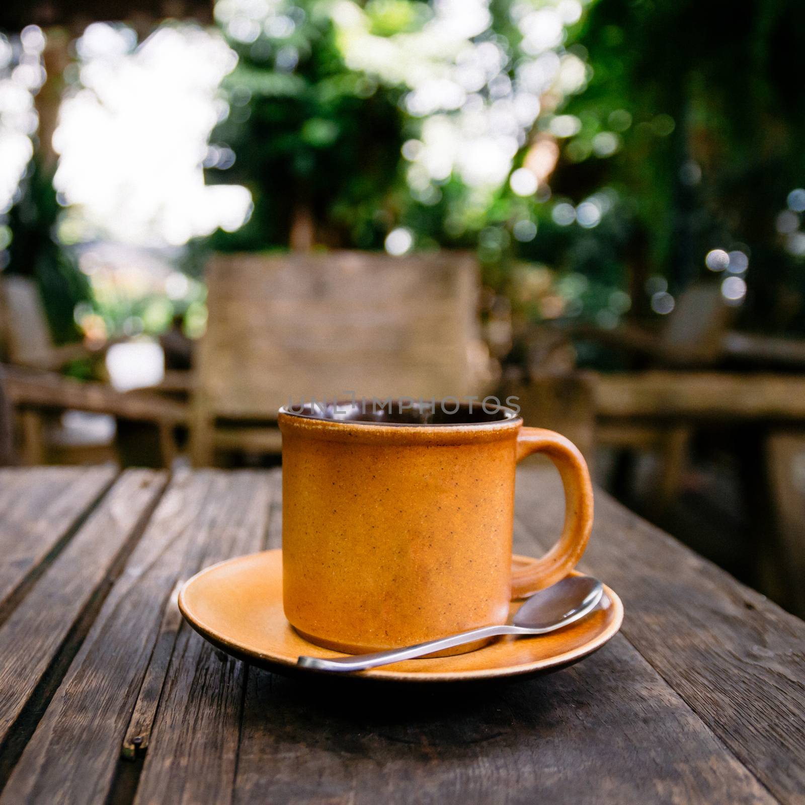 Cup of coffee on the wooden table in cafe. Films grain filter.