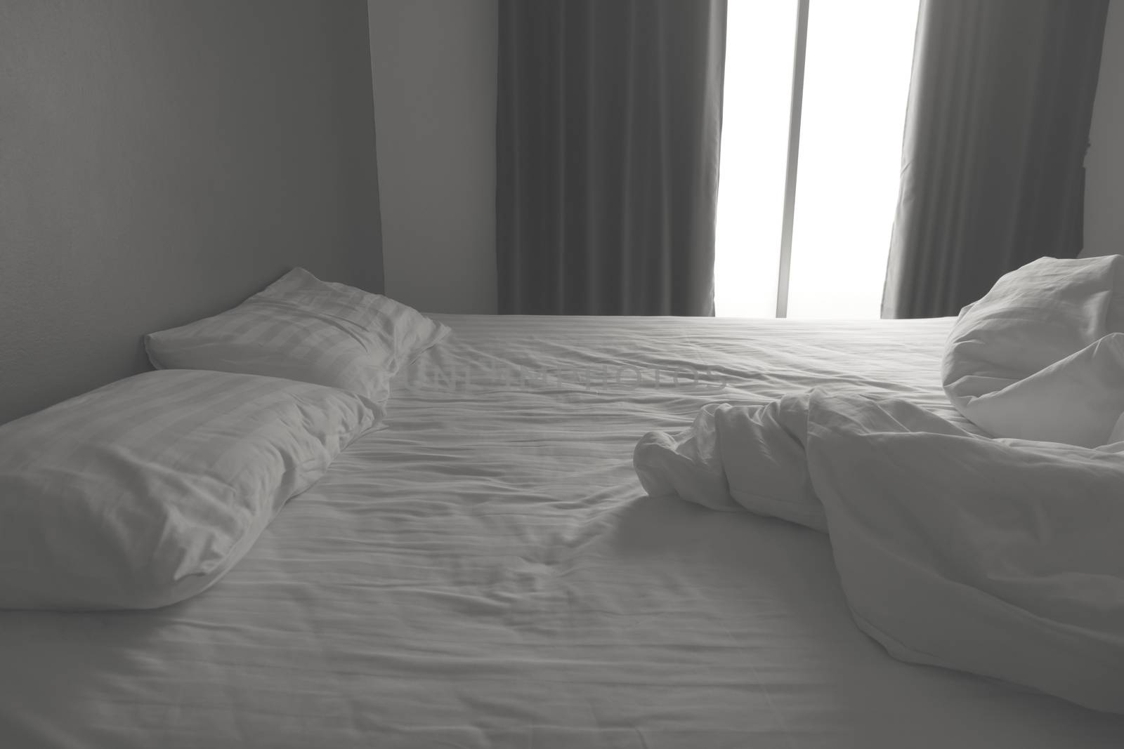 Messy white bedding sheets and pillows. black and white tone