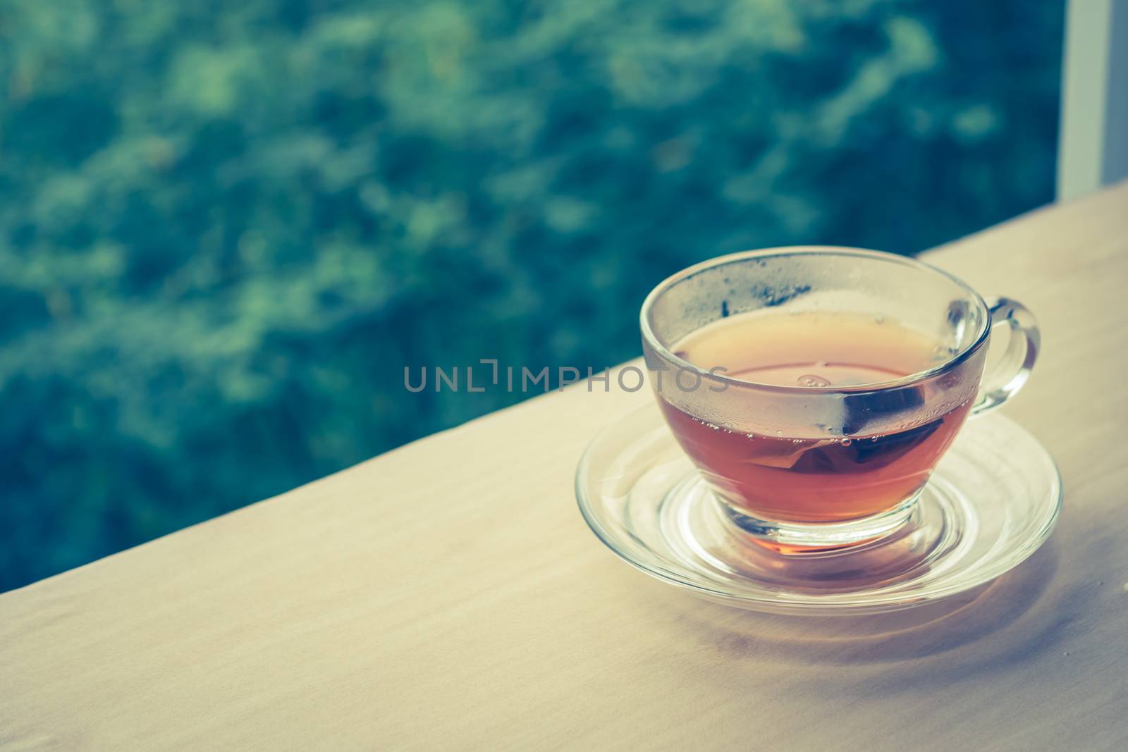 A cup of tea on the wooden table, tea bag in glass, nature background. Vintage tone. Free space for text