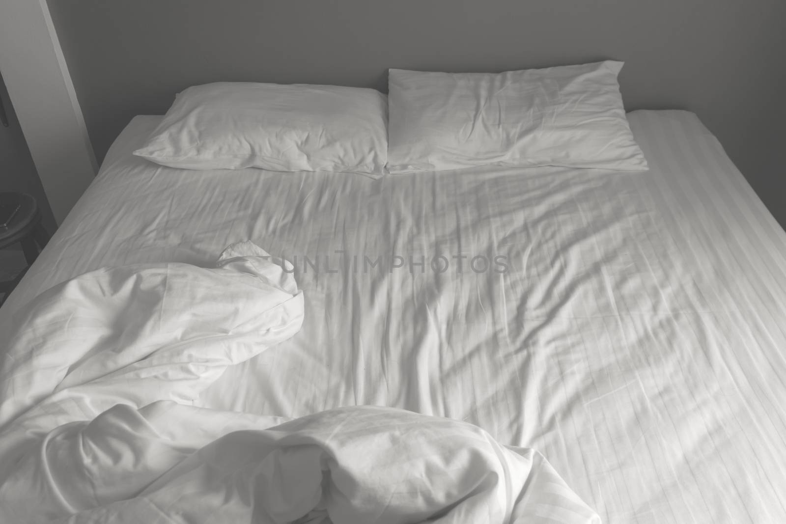 Messy white bedding sheets and pillows. black and white tone
