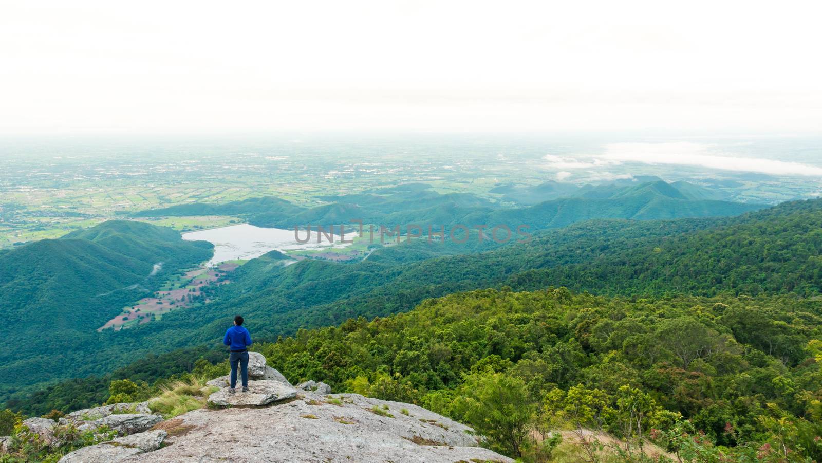 Young man enjoying a valley view from top of a mountain.