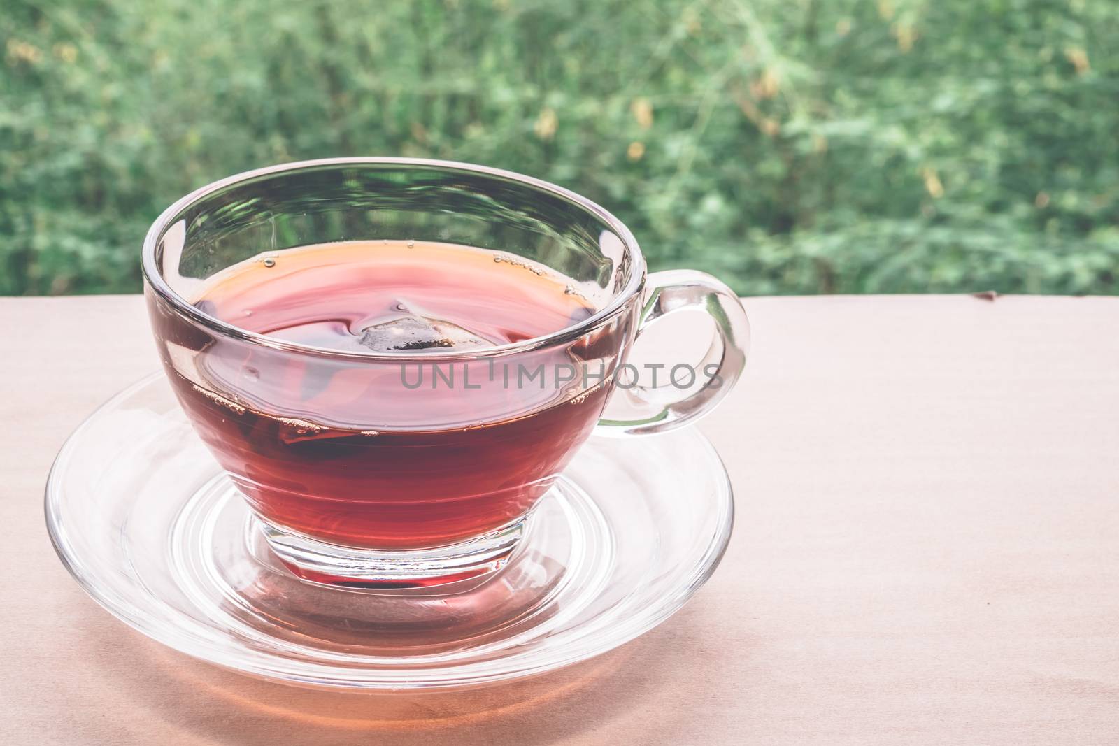 A cup of tea on the wooden table, tea bag in glass, nature background.