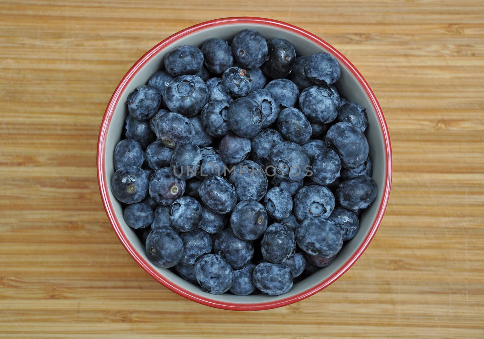 Bowl filled with fresh blueberries on old wooden cutting board