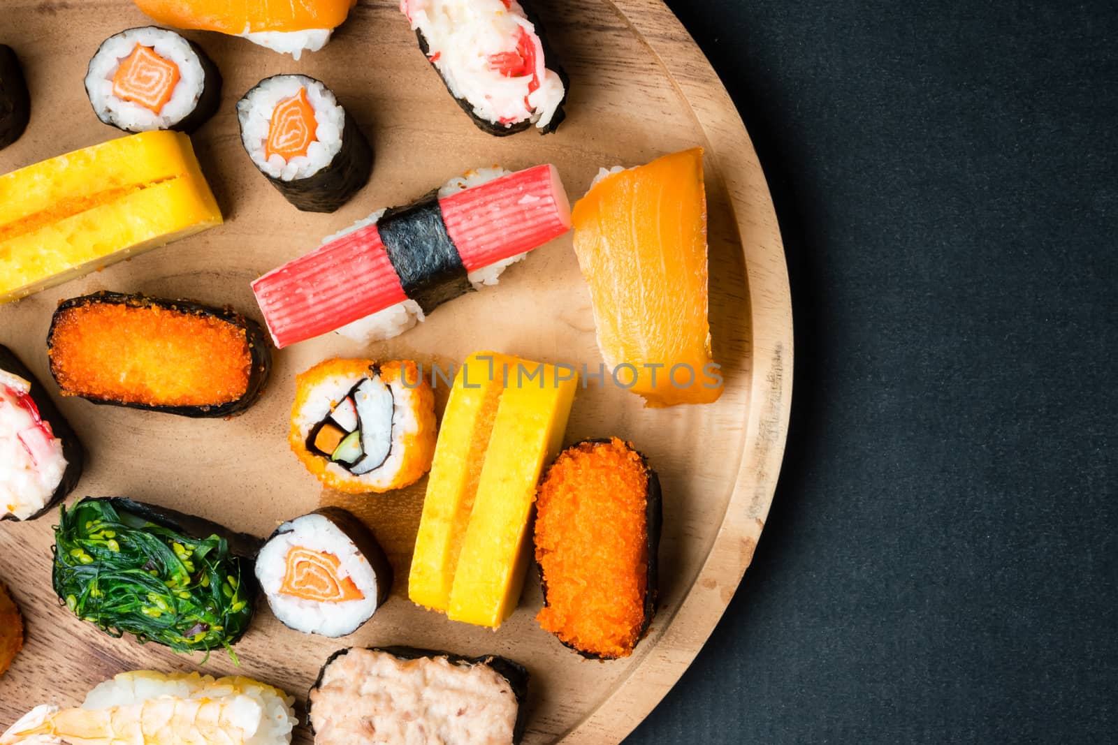 Top view of Sushi set on wooden plate on black background, Japanese food. Free space for text
