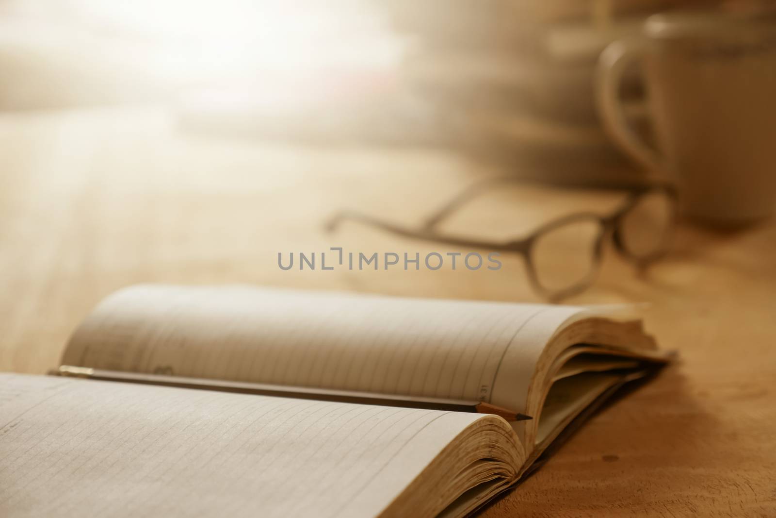 Close up of open notebook with pencil on wooden desk, Soft focus, Flare sunlight, Vintage tone.