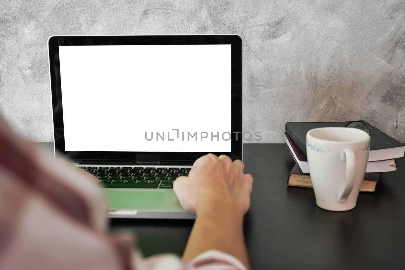 Close up of male hands using laptop with white screen monitor on the desk.