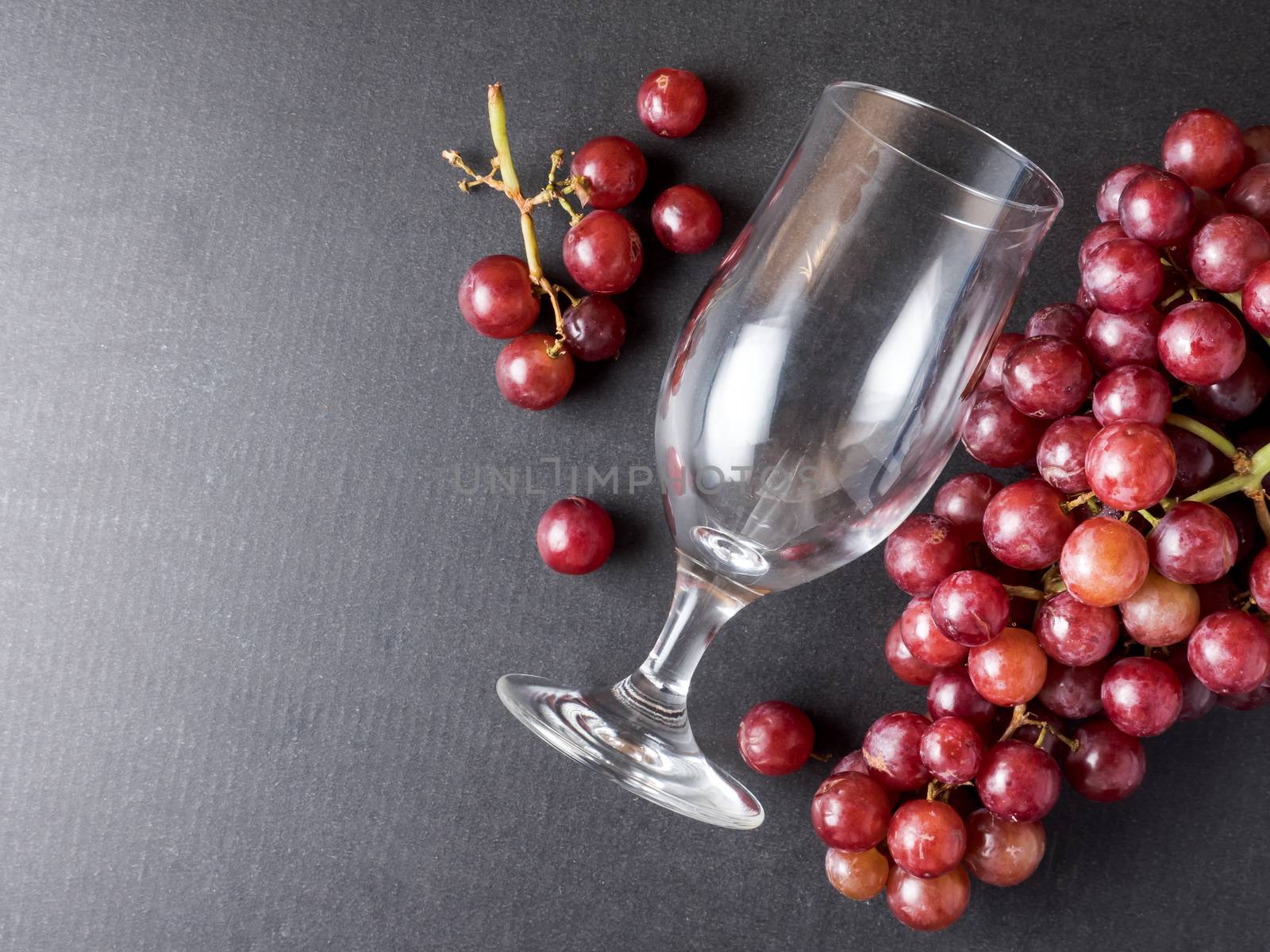 Top view of Red grapes with glass on a black background.
