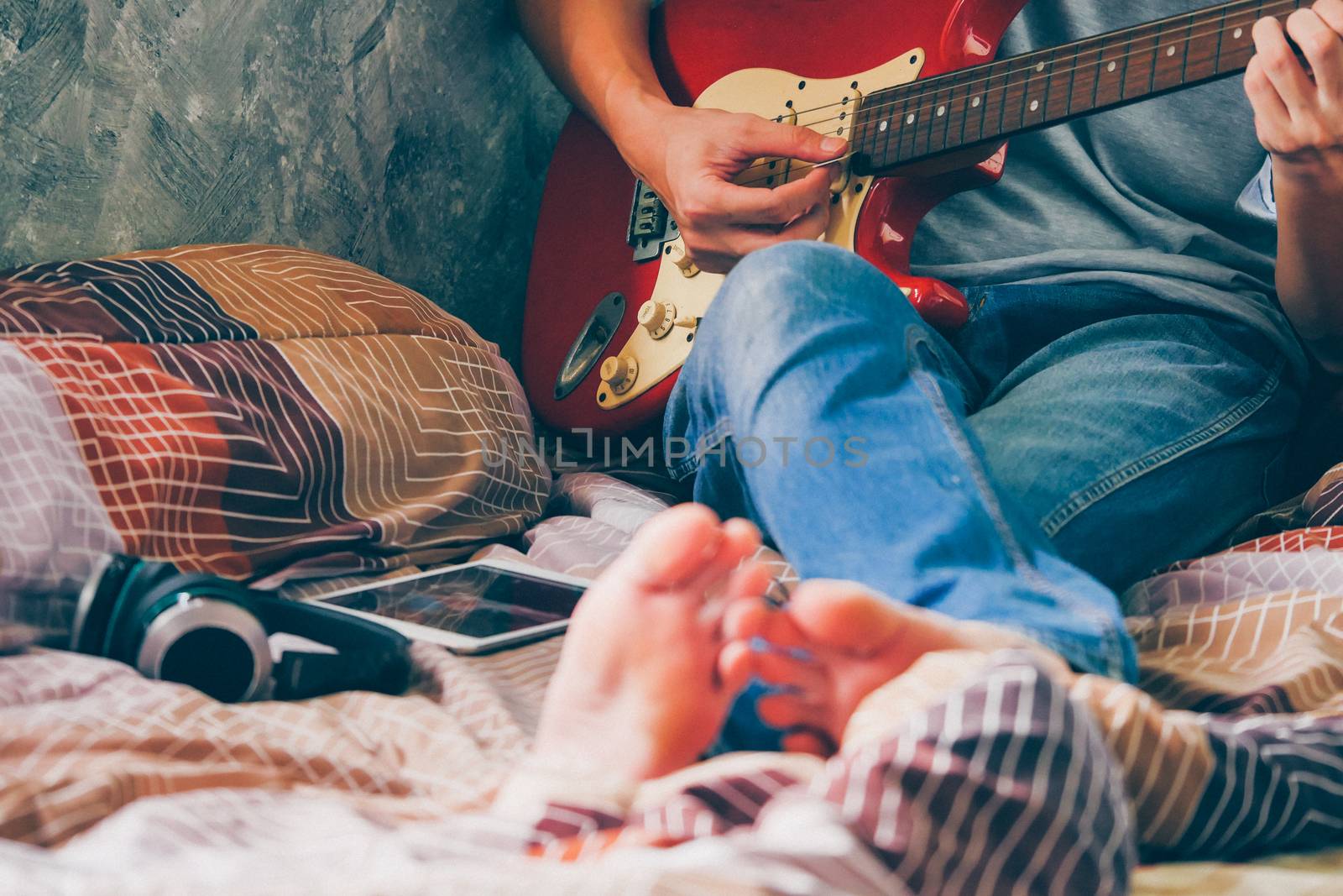 Close up of young man playing electric guitar on his bed, Films grain filter.