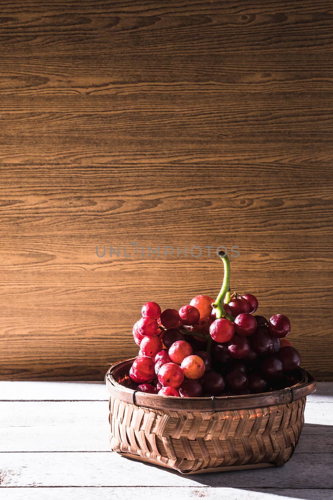 Red grapes in basket on the wooden table. Free space for text