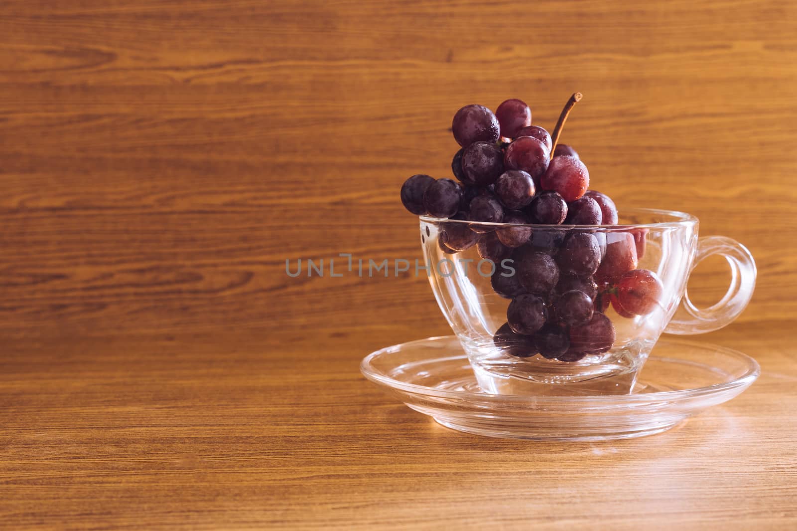 Red grapes in glass on the wooden table. Free space for text