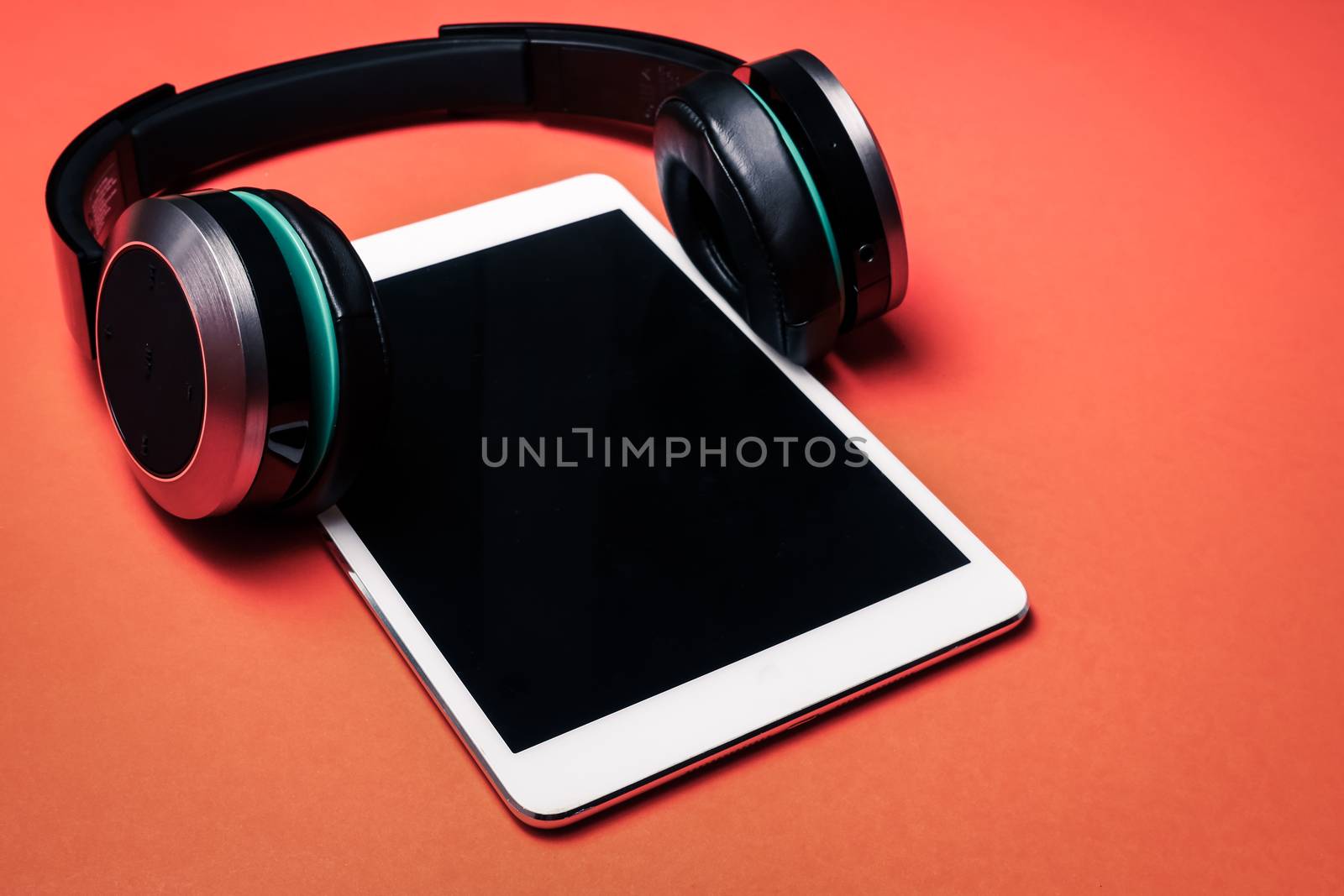 Modern headphones with tablet pc on a orange background.