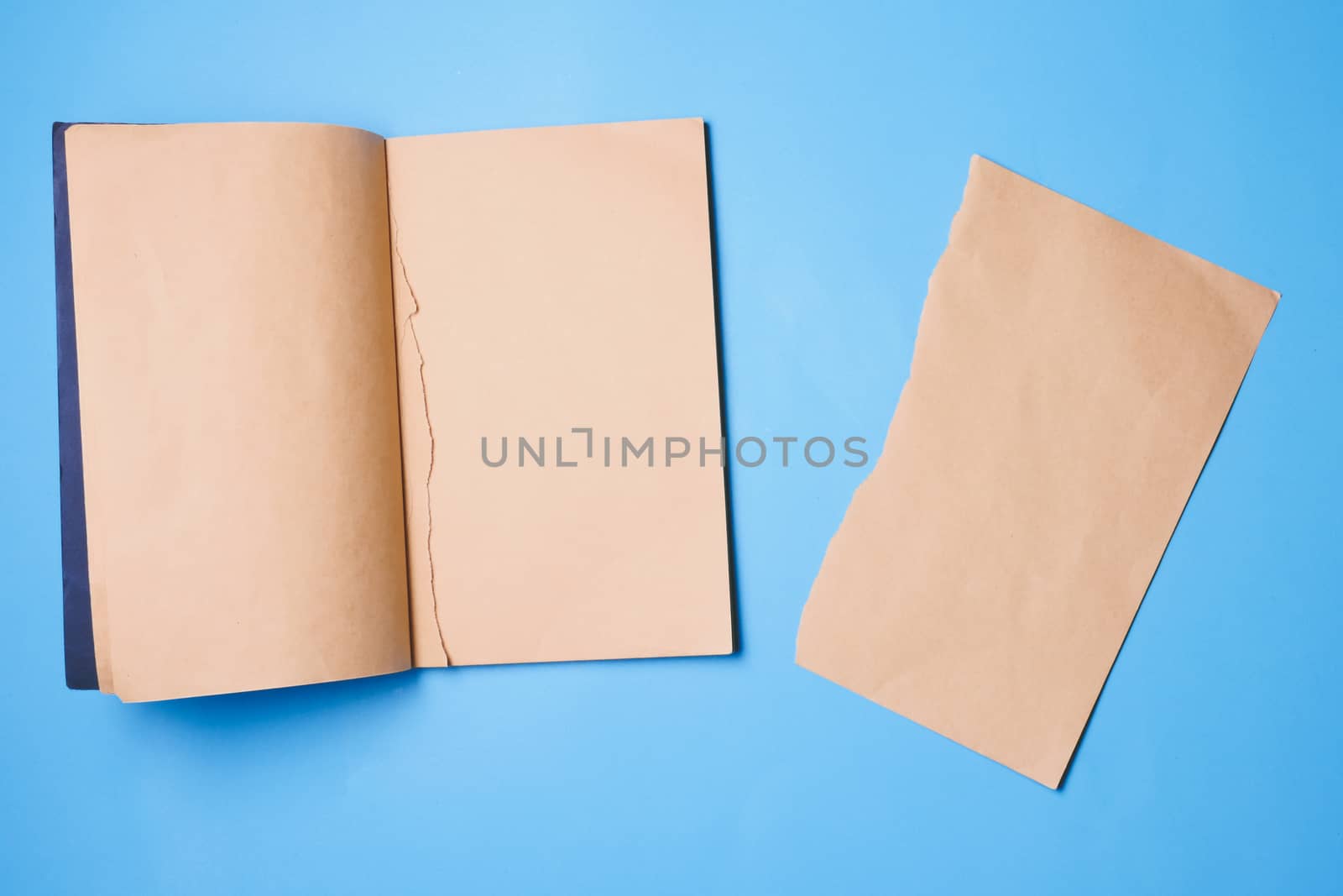 Blank notebook with a piece of note paper on blue background.