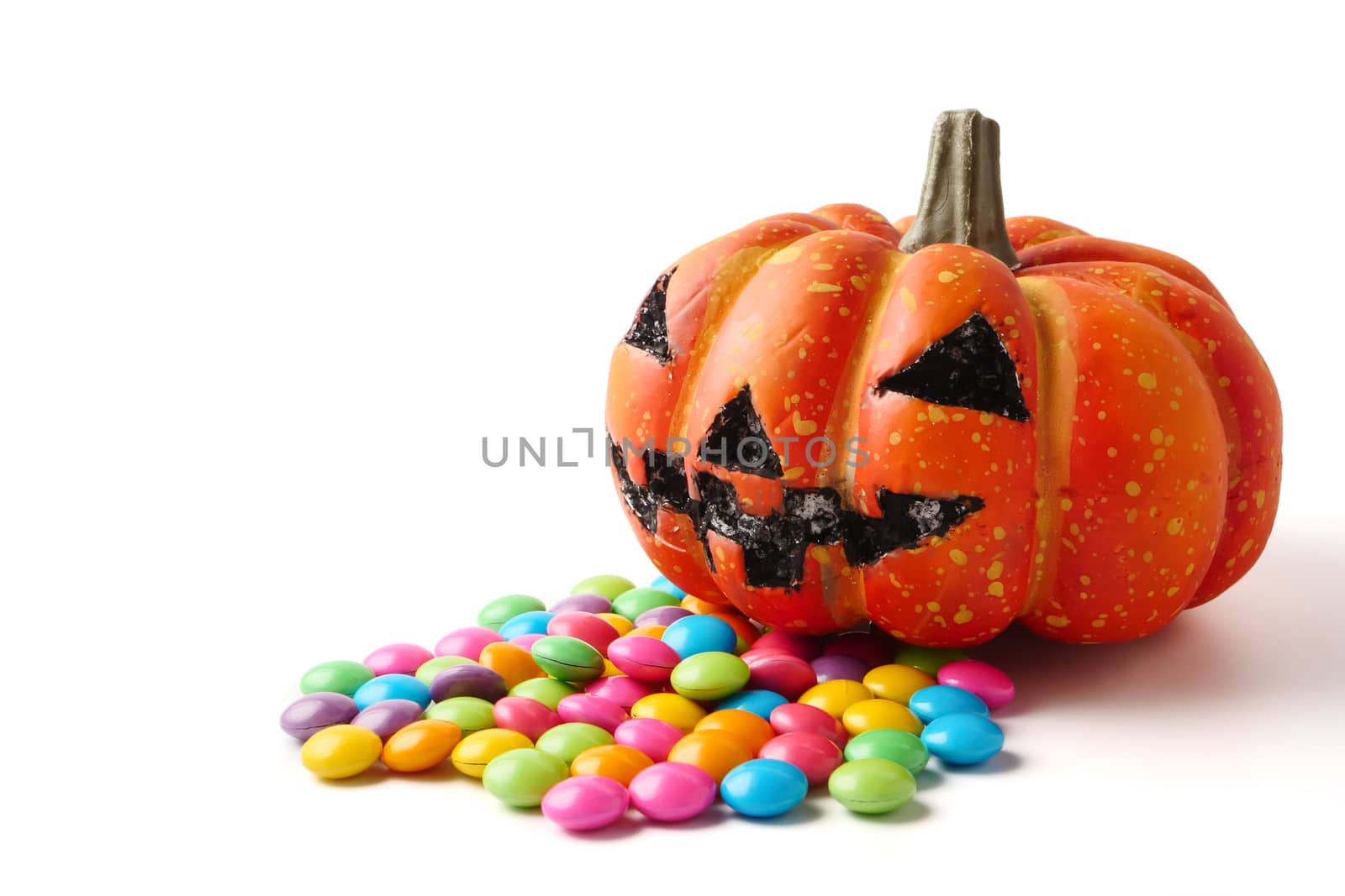 Halloween pumpkin with pile of candy on a white background.